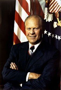 President Gerald Ford, arms folded, in front of a United States Flag and the Presidential seal