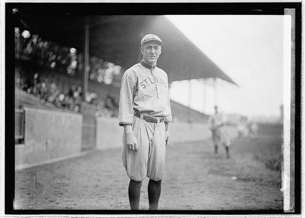 Glass negative of Branch Rickey wearing St. Louis baseball uniform, standing on field with other baseball player in background.