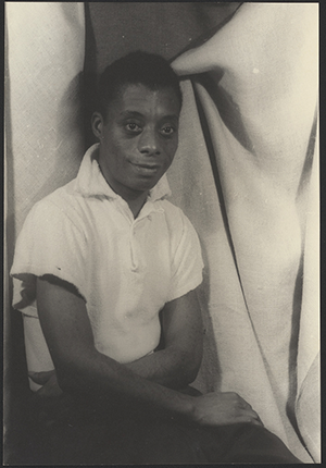 Photograph shows James Baldwin, an African American, male, LGBTQIA writer and activist, seated.
