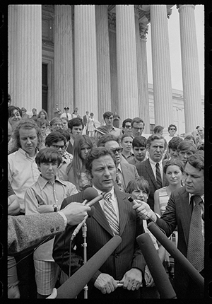 Birch Bayh in front of microphones speaking on the steps of the Supreme Court with reporters and others around him announcing decision on Pentagon Papers Suit. By Warren K. Leffler, photographer, June 30, 1971.