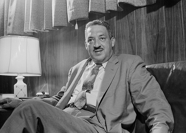 Thurgood Marshall, sitting on couch next to lamp, dressed in suit, three-quarter portrait by Thomas O'Halloran, photographer 1957.