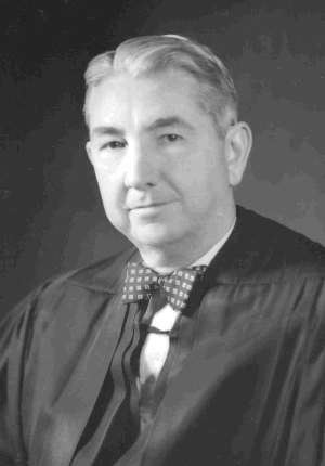 Tom C. Clark, dressed in judicial robe and bow tie, head-and-shoulders portrait, photograph from the Supreme Court of the United States.