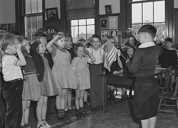 Young students in Norfolk, Virginia, saluting the flag of the United States while reciting the pledge of allegiance. Photograph by John Vachon, 1941.